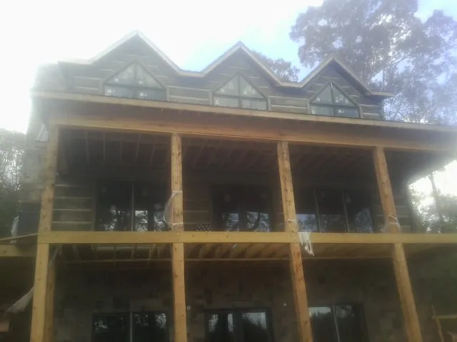 Dormers and porch framing on a large log home under construction — Roof Coating work by our crew in Viborg