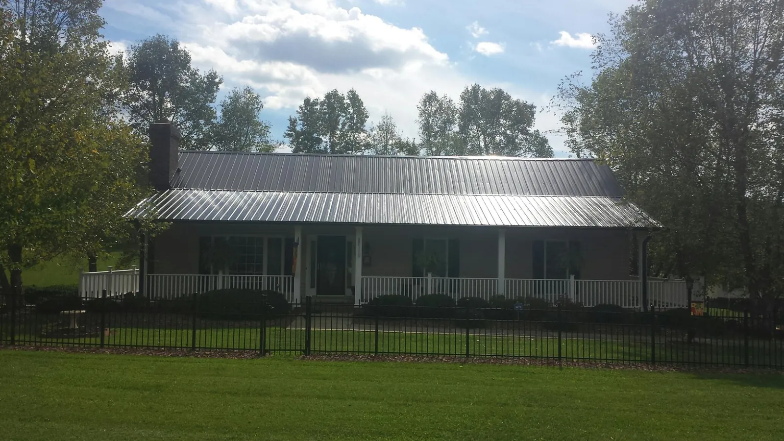 Gray metal roof on a brick ranch with a full width front porch — Gutter Guard Installation work by our crew in Viborg