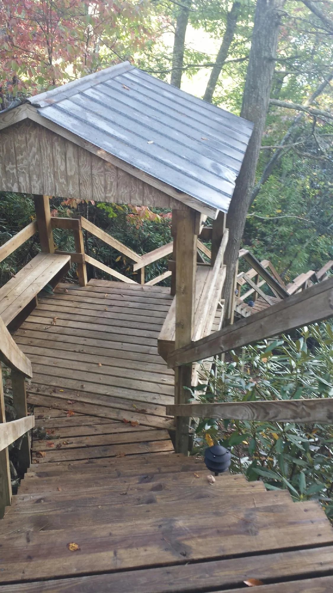 Metal roofed shelter over wooden steps on a wooded walkway — Skylight Repair & Installation work by our crew in Viborg